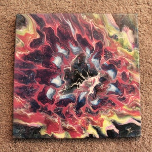 May include: Abstract painting on canvas with swirling red, black, white, and blue colors. The colors create a pattern that resembles a flower.