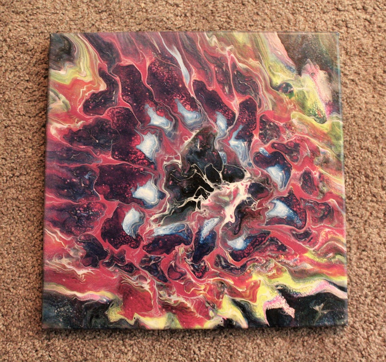 May include: Abstract painting on canvas with swirling red, black, white, and blue colors. The colors create a pattern that resembles a flower.