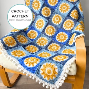 Puede incluir: Una manta de crochet con un borde blanco y un patrón de soles amarillos sobre un fondo azul. La manta está colocada sobre una silla de madera. El texto "CROCHET PATTERN PDF Download" es visible en la esquina superior izquierda de la imagen.
