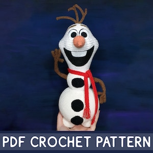 May include: A white crocheted Olaf snowman from the movie Frozen, wearing a red scarf with black tassels. The snowman has a brown twig nose and brown twig hair.  PDF CROCHET PATTERN.