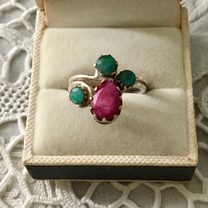 Op de afbeelding: Een zilveren ring met een roze peervormige edelsteen en drie kleinere groene edelstenen.