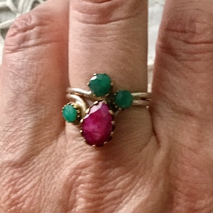 Peut inclure: Une bague en argent avec une pierre précieuse rose en forme de poire et trois pierres précieuses vertes.