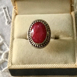 Peut inclure: Une bague en argent avec une grande pierre rouge ovale sertie dans une bélière à perles.