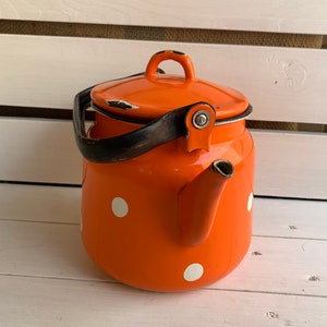 May include: Orange enamel teapot with white polka dots and a black handle.
