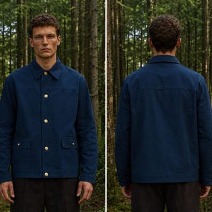 May include: A navy blue long-sleeve jacket featuring a classic collar, a front button placket with metallic gold-toned buttons, and two front patch pockets with buttoned flaps. The garment is shown from both the front and back perspectives.