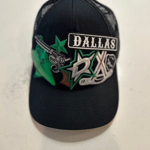 Può includere: Cappellino da camionista nero in rete con una stella verde, una pistola e una toppa Dallas. Il cappello ha anche una toppa a stella bianca e verde con le lettere "DX" su di essa.