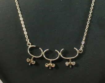 May include: A silver chain necklace with a pendant featuring three connected curved shapes with small round accents.