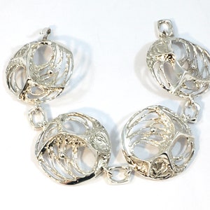 May include: Silver bracelet with four round, openwork links. Each link has a textured, organic design.