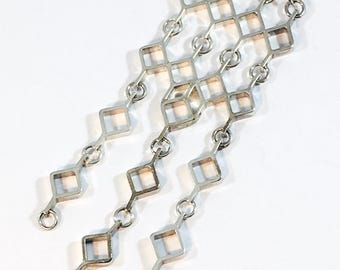 May include: A silver necklace with a geometric design. The pendant is made of multiple interconnected diamond shapes.