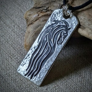 May include: A silver pendant necklace with a textured surface and a black horse head design.