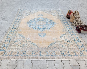 May include: A vintage rug with a light beige background and a blue and cream patterned design. The rug has a worn and faded look, giving it a rustic and antique feel.