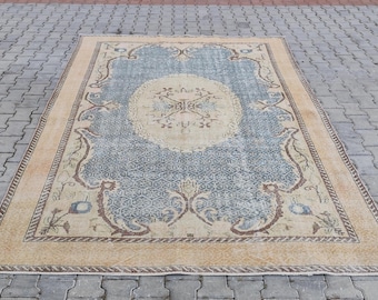 May include: A vintage rug with a blue and beige color scheme. The rug has a central medallion with a floral design and a border with a repeating pattern.