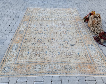 May include: A vintage rug with a beige background and a blue and brown geometric pattern. The rug has a faded look and is in good condition.