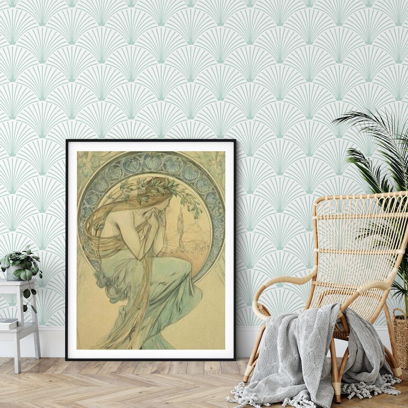 A room with art deco wallpaper behind a wicker chair and a plant and a large framed art nouveau portrait.