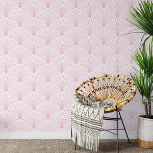 Pink art deco wallpaper behind a boho wicker chair and a plant