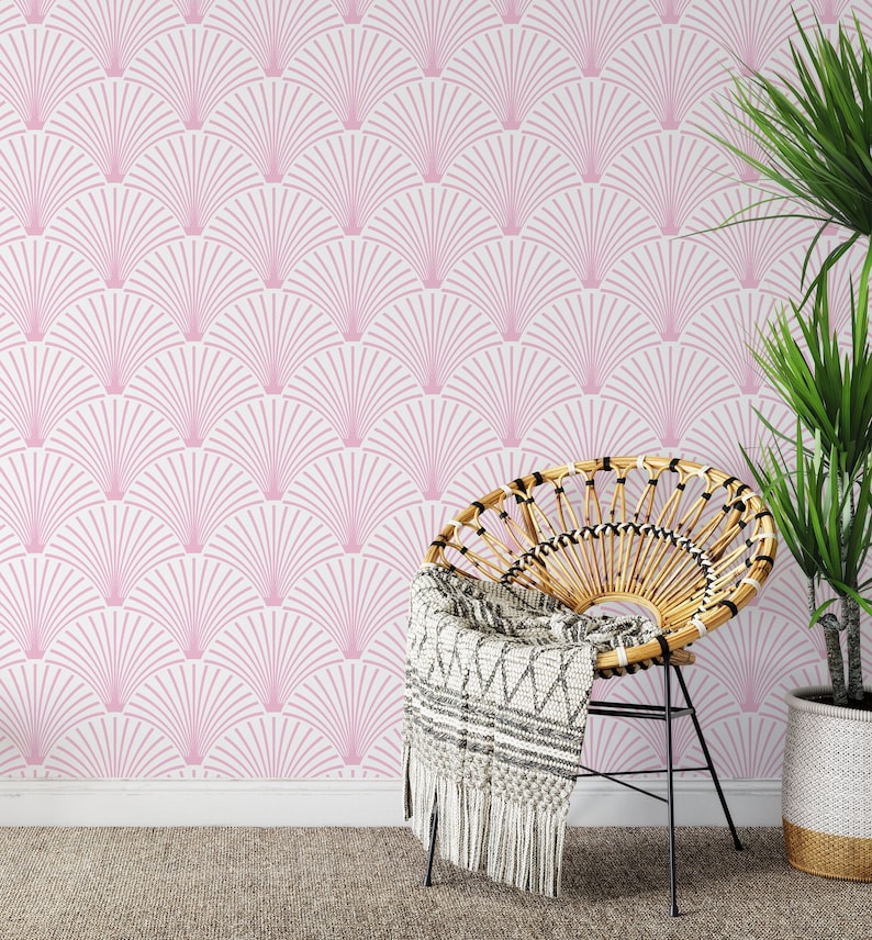 Pink art deco wallpaper behind a boho wicker chair and a plant