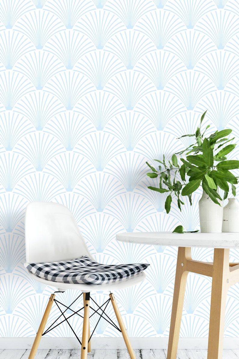 Light blue art deco wallpaper on a wall behind a chair and a table with a plant on it.