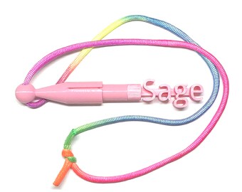 May include: Pink plastic name tag with the name "Sage" in pink letters. The tag is attached to a rainbow lanyard.