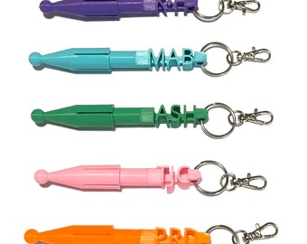 May include: Five colorful keychain tools with a pointed tip and a retractable design. Each keychain has a different name spelled out in block letters: KJH, MAB, ASH, TJC, and PRD.