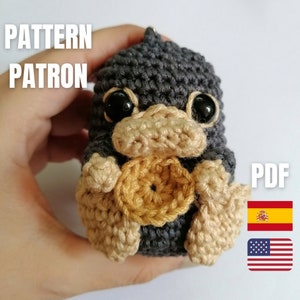 Może przedstawiać: Szydełkowana pluszowa zabawka Niffler w odcieniach szarości, beżu i złota, z dużymi czarnymi oczami. Obraz zawiera tekst "PATTERN PATRON" i "PDF".
