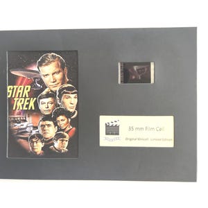May include: A framed Star Trek film cell. The image features a collage of actors from the original series, with the Star Trek logo. A small film cell and a label that reads "35 mm Film Cell" are also included.