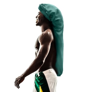 Puede incluir: Un gorro de satén verde azulado, diseñado para proteger el cabello, usado por una persona. El gorro es largo y cubre la cabeza y parte de la espalda. La persona lleva pantalones cortos blancos y verdes. El fondo es blanco.