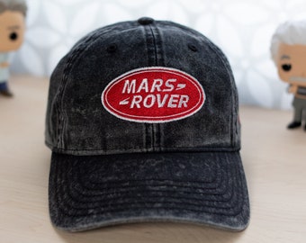 May include: A black denim baseball cap with a red oval patch that says "MARS ROVER" in white lettering.