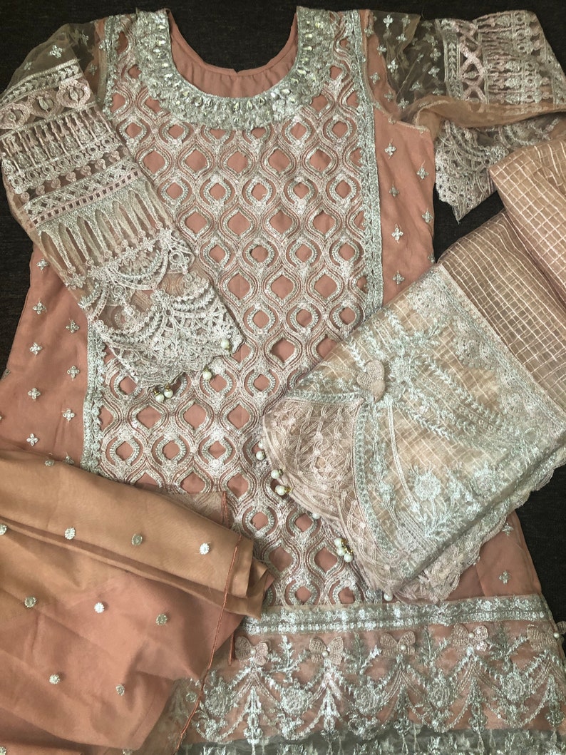 May include: A light brown dress with silver embroidery and embellishments. The dress has a long sleeve and a matching dupatta.
