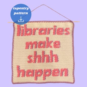 May include: A cream-coloured, crocheted tapestry with the phrase "libraries make shhh happen" in pink lettering. The square tapestry has a pink border and is suspended from a wooden dowel. A blue circle in the upper left corner reads "tapestry pattern".