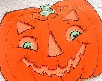 May include: Orange jack-o'-lantern decoration with green eyes and a smiling mouth. The Halloween-themed decoration is on a white, lacy doily. A black candle and black rose are in the background.