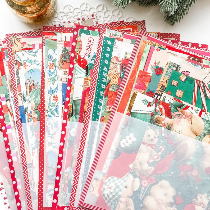 May include: A stack of vintage Christmas cards with red, green, and white designs. The cards feature a variety of holiday themes, including Santa Claus, reindeer, and snowmen. The cards are arranged in a fan shape, with the top card showing a red and white polka dot pattern.