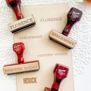 May include: Four wooden rubber stamps with dark red handles, each labeled Hathaway Stamp Co. Cincinnati, Ohio. The stamps feature the names Florence, Beechmont, Western Woods, and Houck, which are also printed on the paper card below.