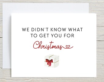 May include: A white card with red text that reads "We didn't know what to get you for Christmas." A small white gift box with a red bow is illustrated below the text.