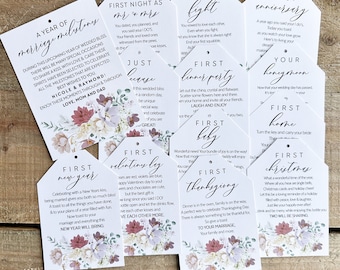 May include: White tag-shaped cards with floral designs and various phrases like "First Anniversary" and "First Christmas." The cards are arranged on a wooden surface, ideal for wedding or anniversary gifts.