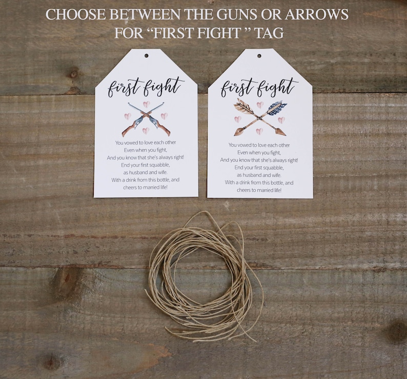 May include: Two white tags with the text "first fight" printed in pink. The tags feature a watercolour illustration of either guns or arrows crossed with hearts. The text on the tags reads: "You vowed to love each other Even when you fight, And you know that she's always right! End your first squabble, as husband and wife With a drink from this bottle, and cheers to married life!"