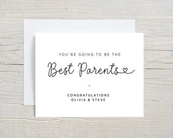 May include: White card with black text that reads "You're going to be the Best Parents" with a small pink heart. Below the text is "Congratulations Olivia & Steve".