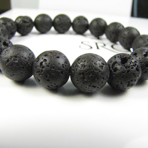May include: A black lava rock beaded bracelet. The beads are round and have a rough, textured surface.