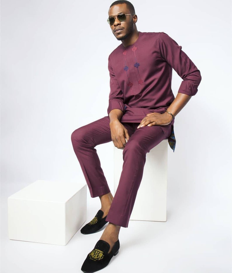 May include: A maroon long-sleeved shirt with embroidered details and matching pants. The person is wearing black loafers with gold embroidery.