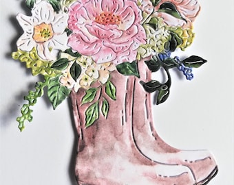 以下が含まれることがあります： ピンクのゴム長靴に、ピンク、白、黄色の花束が詰められています。花には、バラ、アジサイ、ユリが含まれています。