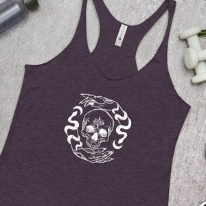 May include: A purple racerback tank top with a white graphic of a skull surrounded by snakes and hands.