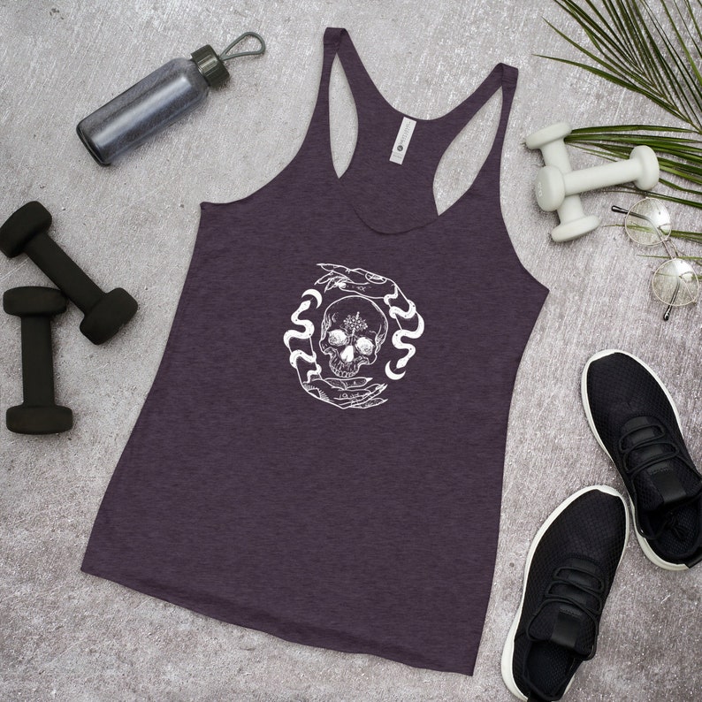 May include: A purple racerback tank top with a white graphic of a skull surrounded by snakes and hands.