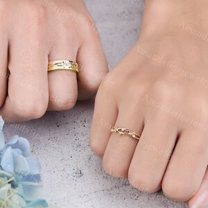Puede incluir: Dos anillos de oro en los dedos de una persona. Un anillo tiene un delicado dise&ntilde;o de espinas con peque&ntilde;as piedras transparentes. El otro anillo tiene un dise&ntilde;o texturizado.