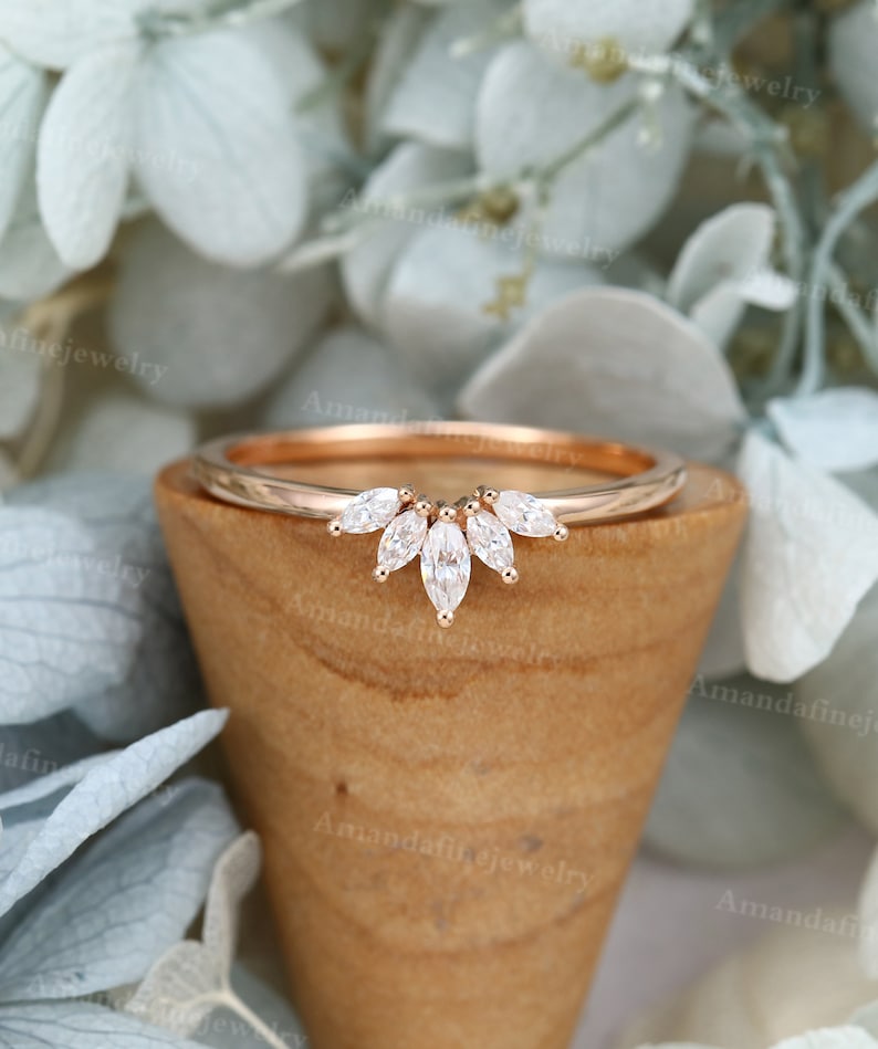 Op de afbeelding: Een delicate band van ros&eacute;goud met een gebogen rij marquise-vormige diamanten. De diamanten zijn gezet in een kraalbezetting en cre&euml;ren een prachtig, sprankelend ontwerp.