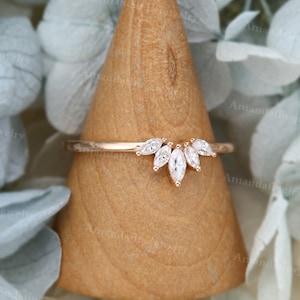 Op de afbeelding: Een ring van ros&eacute;goud met een band van marquisevormige diamanten. De band is bezet met een rij marquisevormige diamanten die een gebogen vorm vormen.