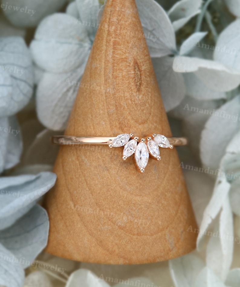 Op de afbeelding: Een ring van ros&eacute;goud met een band van marquisevormige diamanten. De band is bezet met een rij marquisevormige diamanten die een gebogen vorm vormen.