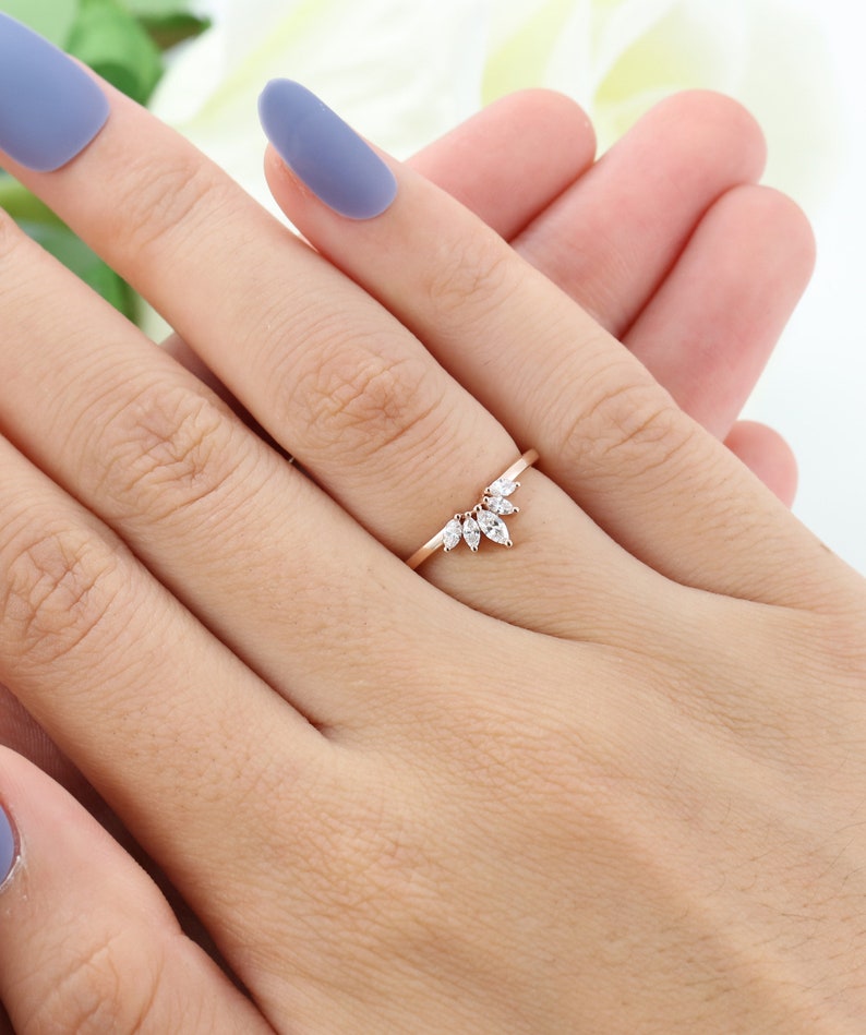 Op de afbeelding: Een delicate ring van ros&eacute;goud met een marquise-vormig diamantclusterontwerp. De diamanten zijn in een aflopend patroon gezet, wat een unieke en elegante uitstraling cre&euml;ert.