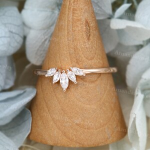Op de afbeelding: Een delicate ring van ros&eacute;goud met een band van marquise-vormige diamanten. De band heeft een rij van vijf marquise-vormige diamanten die in een gebogen, halvemaanvorm zijn gezet.
