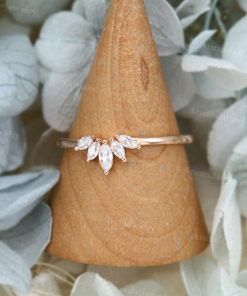 Op de afbeelding: Een delicate ring van ros&eacute;goud met een band van marquise-vormige diamanten. De band heeft een rij van vijf marquise-vormige diamanten die in een gebogen, halvemaanvorm zijn gezet.