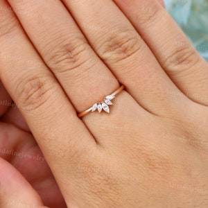Op de afbeelding: Een delicate ring van ros&eacute;goud met een gebogen band en een rij marquise-vormige diamanten die in een V-vorm zijn gezet.