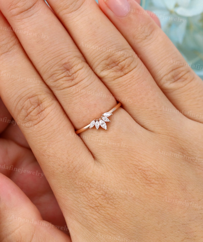 Op de afbeelding: Een delicate ring van ros&eacute;goud met een gebogen band en een rij marquise-vormige diamanten die in een V-vorm zijn gezet.